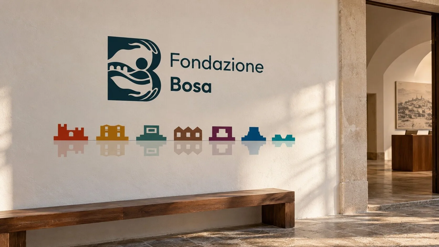 Una parete chiara di museo con il marchio orizzontale della Fondazione Bosa in Blu Temo e, sotto, il fregio dei sette luoghi a colori specchiato sopra una panca di legno